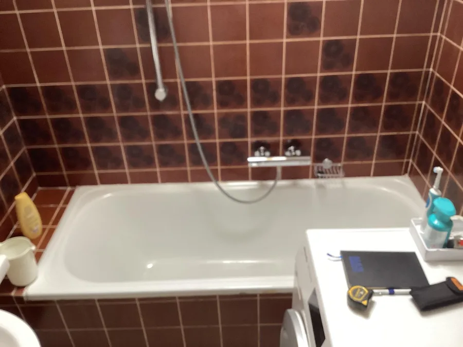 Badkamer in Tilburg met bruine jaren-70-tegels en ligbad, vóór de renovatie